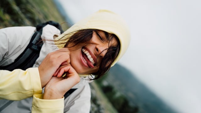 A couple in summery hiking clothes climbing up a rock