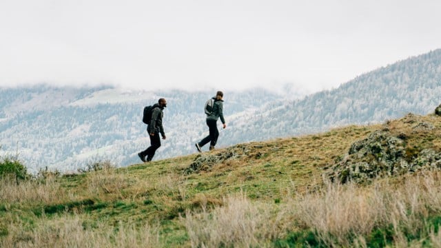 Woman by the side of a lake in a summery outdoor outfit and balancing on small rocks
